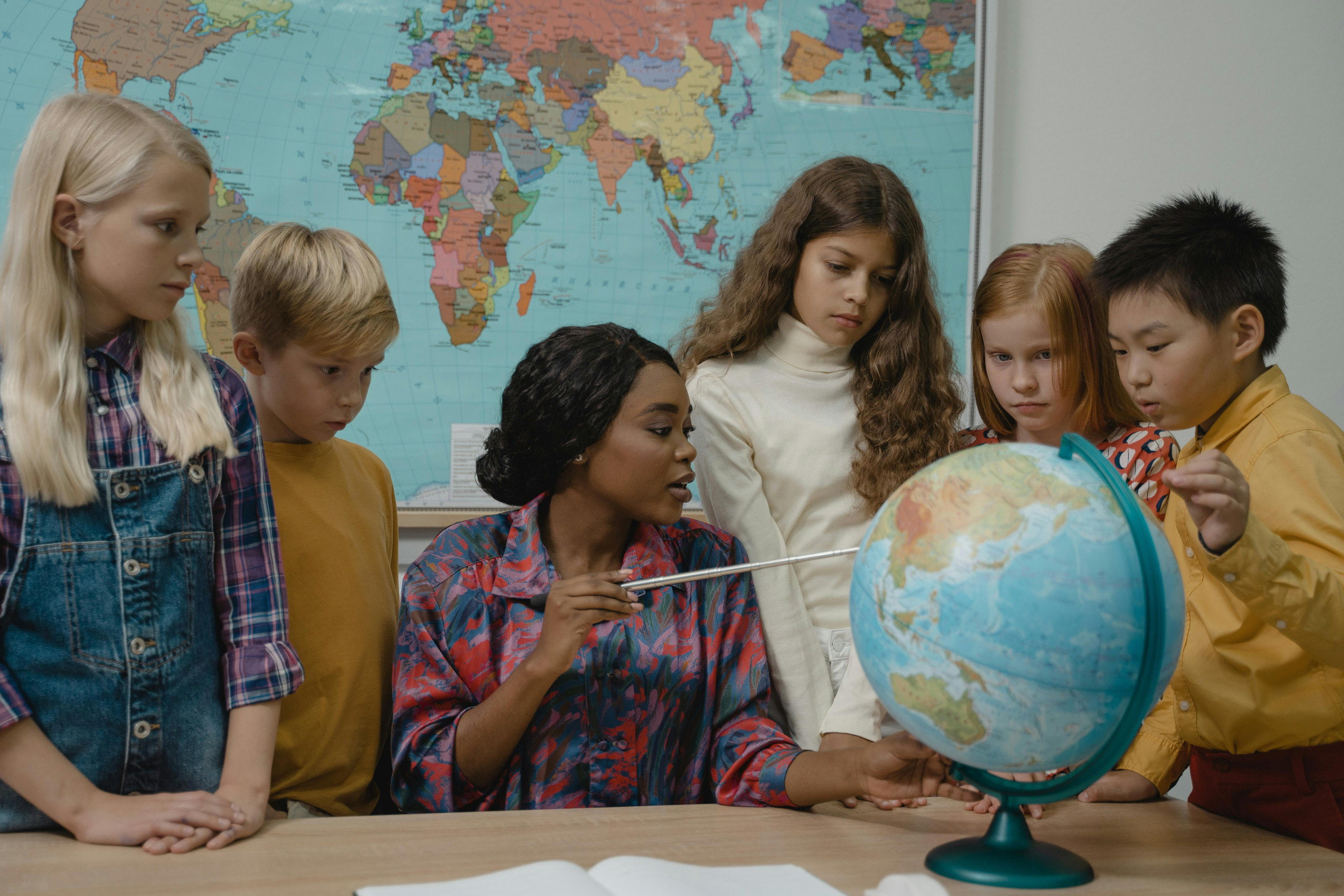 Students exploring a globe with their teacher
